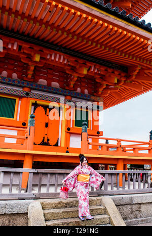 Portrait of woman in traditional dress, standing on steps in front of Kiyomizu-dera Temple, Kyoto, Japan Stock Photo