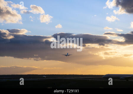 Passanger airplane is flying up in front of bright dusk Stock Photo