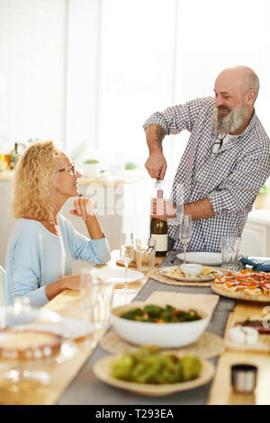 Cheerful senior man opening wine bottle Stock Photo