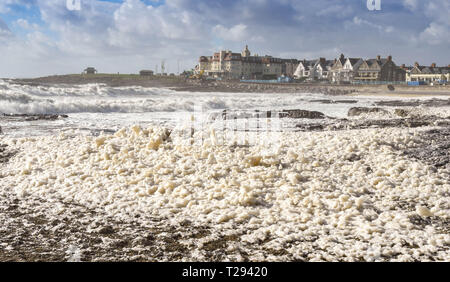 PORTHCAWL, WALES - SEPTEMBER 2018: Masses of sea foam blowing on to the beach in Porthcawl as the tide comes in Stock Photo