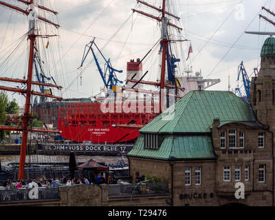 Hamburg, Germany - May 11, 2018: View at outdoor part of Hard Rock Cafe In Hamburg, with sail ship andcontainer vessel  in shipyard in background. Eve Stock Photo