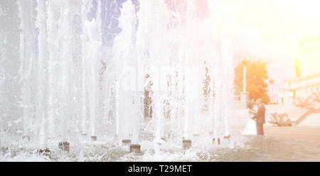 groom and the bride standing behind the fountain in the square. Stock Photo