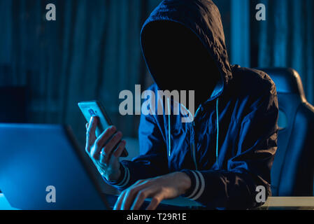 Anonymous hacker programmer uses a laptop to hack the system in the dark. Creation and infection of malicious virus. The concept of cybercrime and hac Stock Photo