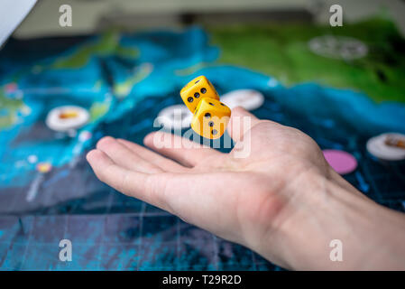 The hand throws yellow dice on the playing field. Luck and excitement. The concept of Board games. Gaming moments in dynamics Stock Photo