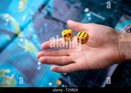 The hand throws two yellow dice on the playing field. Luck and excitement. The concept of Board games. Gaming moments in dynamics Stock Photo