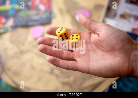 The hand throws two yellow dice on the playing field. Luck and excitement. The concept of Board games. Gaming moments in dynamics Stock Photo