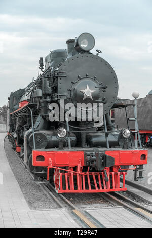 Black vintage steam locomotive with red wheels on the railway. Stock Photo