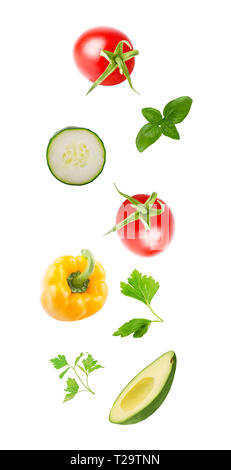 Flying vegetable concept. Fresh organic tomato, cucumber, avocado, sweet yellow pepper and herbs isolated on white background with clipping path as pa Stock Photo