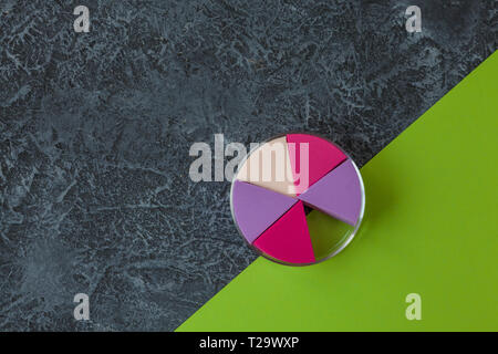 Make up sponges on dark stone background. Cosmetic applicator, green paper with copy space Stock Photo
