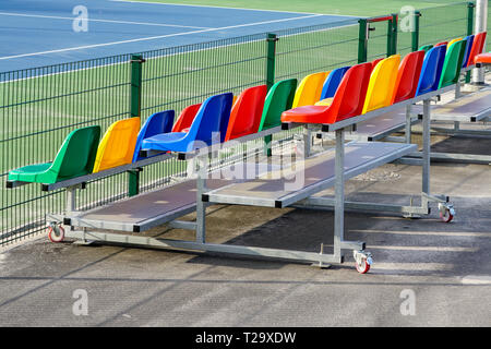portable small size metal stands with colorful plastic seats for spectators in the stadium Stock Photo
