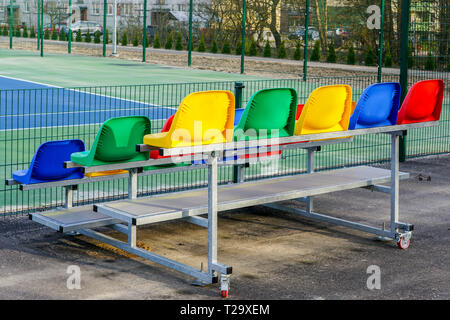 portable small size metal stands with colorful plastic seats for spectators in the stadium Stock Photo