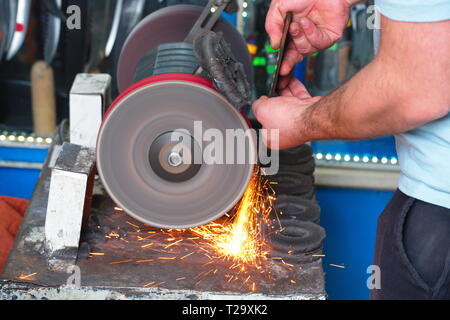 knife sharpening machine and master. Grinding machine. grinding knife using abrasive stone Stock Photo