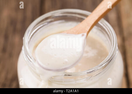 Fresh homemade bubbly sourdough starter, a fermented mixture of water and flour to use as leaven for bread baking, on wooden spoon Stock Photo