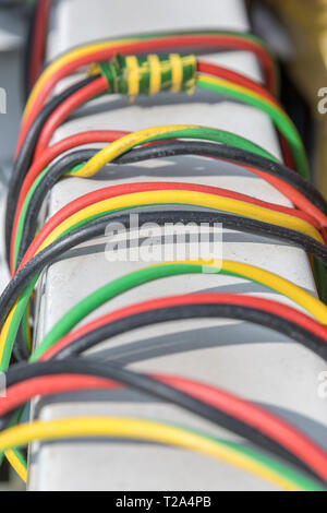 Coloured electrical wires wrapped round industrial light removed from its fixing point to be discarded. Abstract electricity production & distribution Stock Photo
