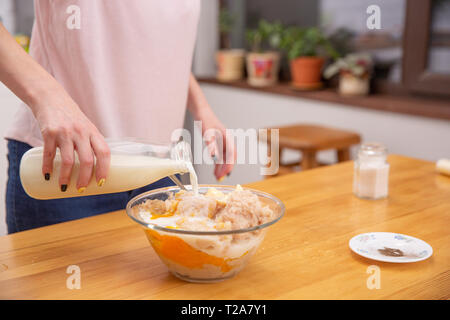 Cooking chicken sausages. pouring milk to minced chicken. cooking process Stock Photo