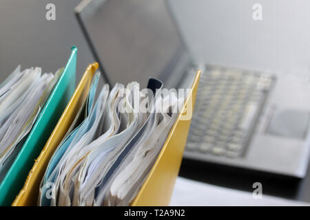 Ring binders filled with papers in front of laptop computer on office table. Selective focus Stock Photo
