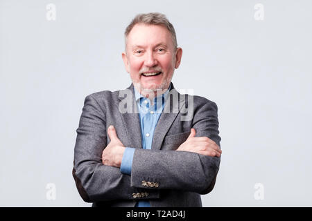 Senior european man in suit and glasses looking at camera and laughing on funny joke. Isolated studio shoot. Stock Photo