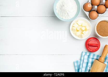 Baking ingredients on white background. Kitchen timer, rolling pin, textile, butter, eggs, sugar and flour. Copy space for text, recipe or menu Stock Photo