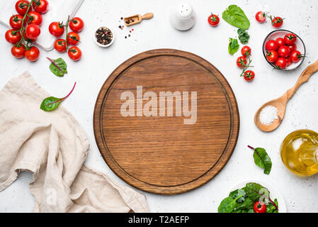 Wooden pizza board and pizza cooking ingredients on white concrete background. Table top view. Copy space for text, recipe, restaurant or cafe menu Stock Photo