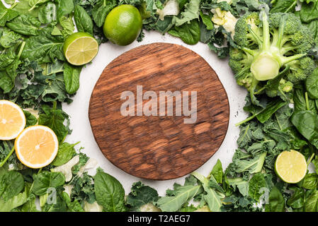 Wooden cutting board and frame of green vegetables. Copy space for text. Concept of cooking food, vegetarian or vegan menu, recipe, healthy eating Stock Photo