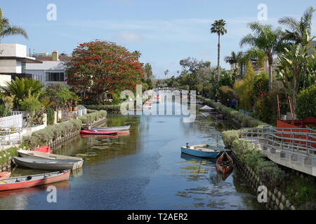 Venice, CA / USA - March 23, 2019: Small boats, homes, and a bridge crossing the water in the Venice Canal Historic District are shown during the day. Stock Photo