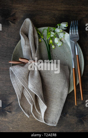 Feastive table setting for holiday Easter dinner decorated with spring snowdrop flowers on rustic table with copy space Stock Photo