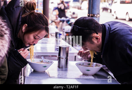 Two people in restaurant, eating bowl of noodles at Tsukiji Fish market, Tokyo, Japan Stock Photo