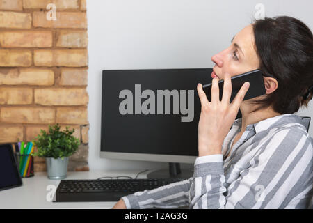 Young office woman talking to someone on her mobile phone Stock Photo