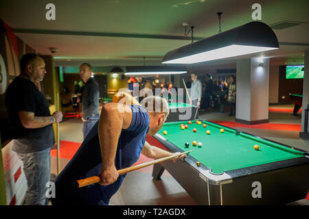 Young man playing pool in pool hall Stock Photo