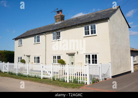Two floors semi detached white country houses with front garden and white fence in England, UK Stock Photo
