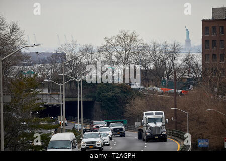 Traffic exiting Brooklyn bridge with the statue of Liberty behind, Manhattan, New York at night Stock Photo