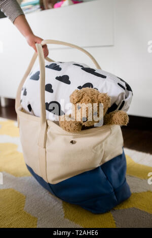 Girl's hand holding bag with blanket and teddy bear Stock Photo