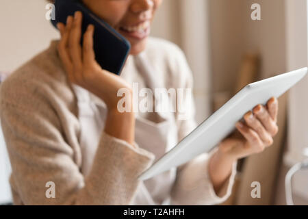 Young woman using digital tablet while taking phone call Stock Photo