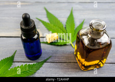 Hemp leafs on wooden table, cannabis oil extracts in bottles Stock Photo