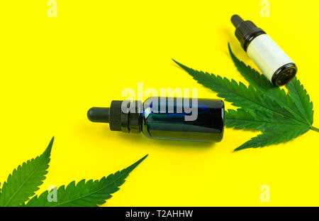 Hemp leafs and cannabis oil extracts in bottles on yellow background Stock Photo