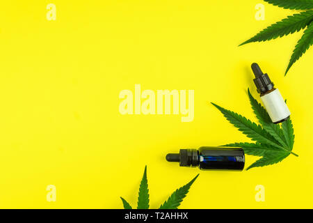 Hemp leafs and cannabis oil extracts in bottles on yellow background Stock Photo