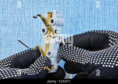 Electrician in protective gloves is mounting new wall plug. Stock Photo