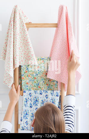 Woman choosing fabric from rack Stock Photo