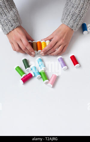 Woman's hands organizing colorful spools of thread Stock Photo