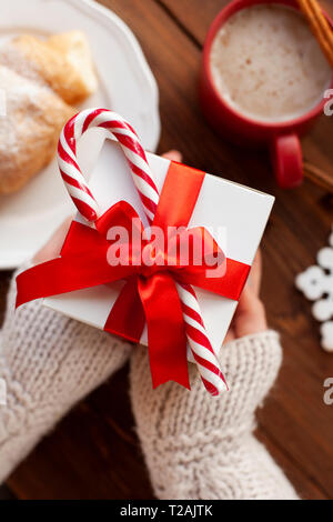 Hands of woman holding Christmas present with candy cane Stock Photo