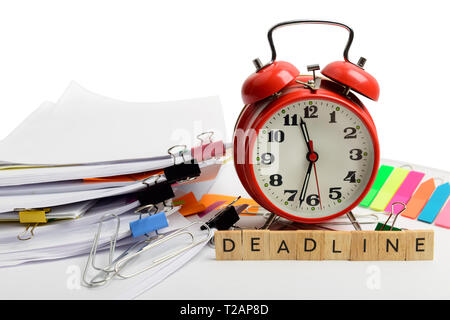 Alarm clock, over pile various documents, reports and receipt with colorful paperclip on white background. Deadline business and finance concepts Stock Photo