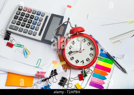 Alarm clock, over pile various documents, reports and receipt with colorful paperclip on white background. Deadline business and finance concepts Stock Photo