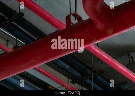 Fire sprinkler system with red pipes hanging from ceiling inside building. Fire Suppression. Fire protection and detector. Main supply water piping Stock Photo