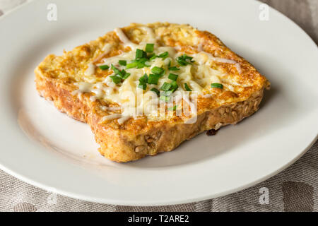 Savoury cheesy French toast slice with chives garnish close up on white plate