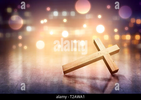 Christian cross on the concrete floor with blurry lights over bright background Stock Photo