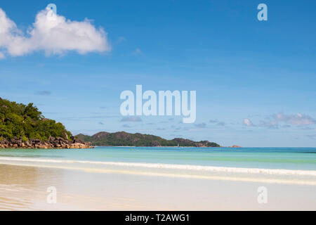 Calm sea on Anse Volbert and a view toward Curieuse Island from Praslin, the Seychelles Stock Photo