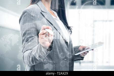 Business woman holding digital tablet and drawing with marker on virtual screen which display the interface of financial chart and world maps. Digital Stock Photo