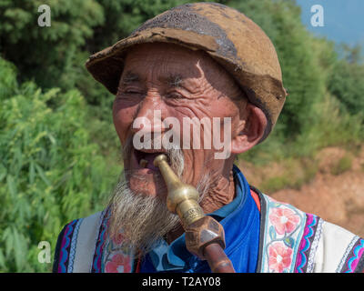 Local Yi mature man smoking a pipe at a small village in the mountains in the Honghe Prefecture, Yuanyang County, Yunnan, China. Stock Photo
