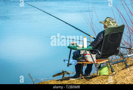 fisherman sits in a chair on the beach with fishing rods and