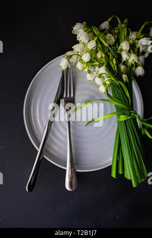 Feastive table setting for holiday Easter dinner decorated with spring snowdrop flowers on rustic table with copy space Stock Photo